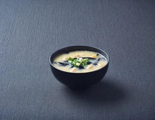 Missosopp Skål med krämig misosoppa, garnerad med grönlök och alger.